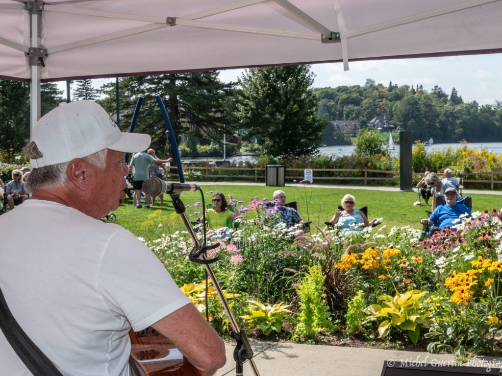 Un homme joue d ela guitare devant des specctateurs rassemblés