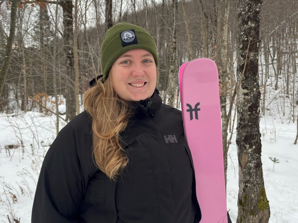 Une jeune femme dehors se tient debout avec ses skis