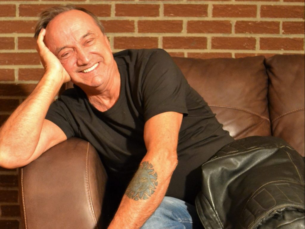 Un homme souriant appuyé sur un accoudoir
